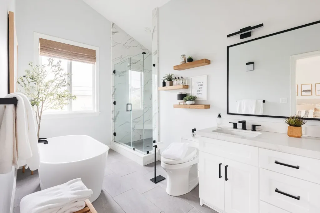 Bright modern bathroom with a freestanding white tub, walk-in glass shower, and minimalist white vanity, showcasing a stylish remodel design.