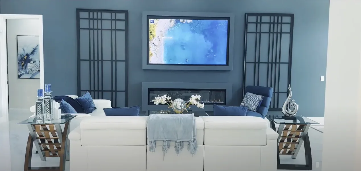 Modernized sunken living room with sleek furniture, navy blue accents, and a flat-screen TV showcasing a beautiful transformation.