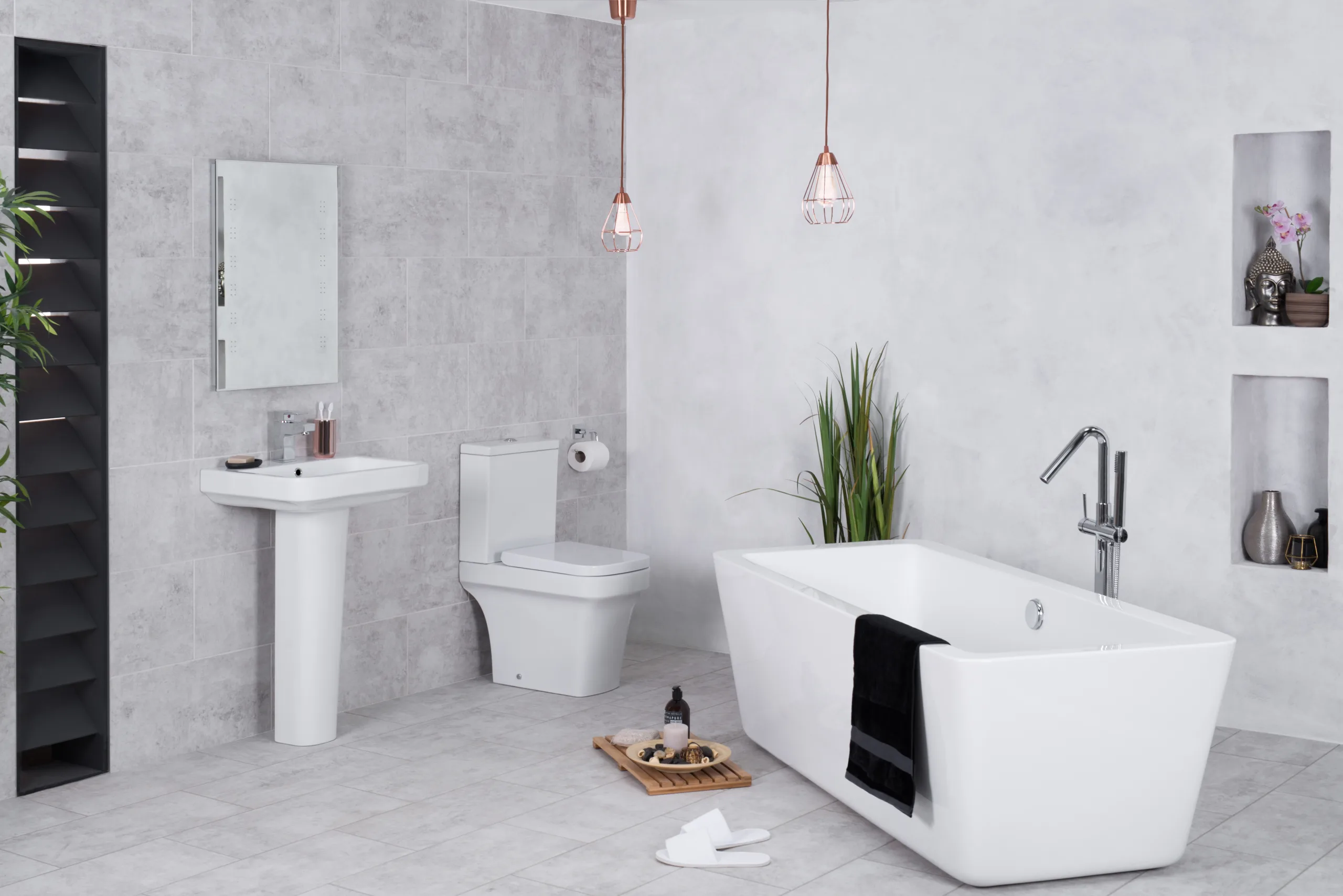 A minimalist bathroom with gray tiles, white appliances, built-in wall decor, and a black tile accent.