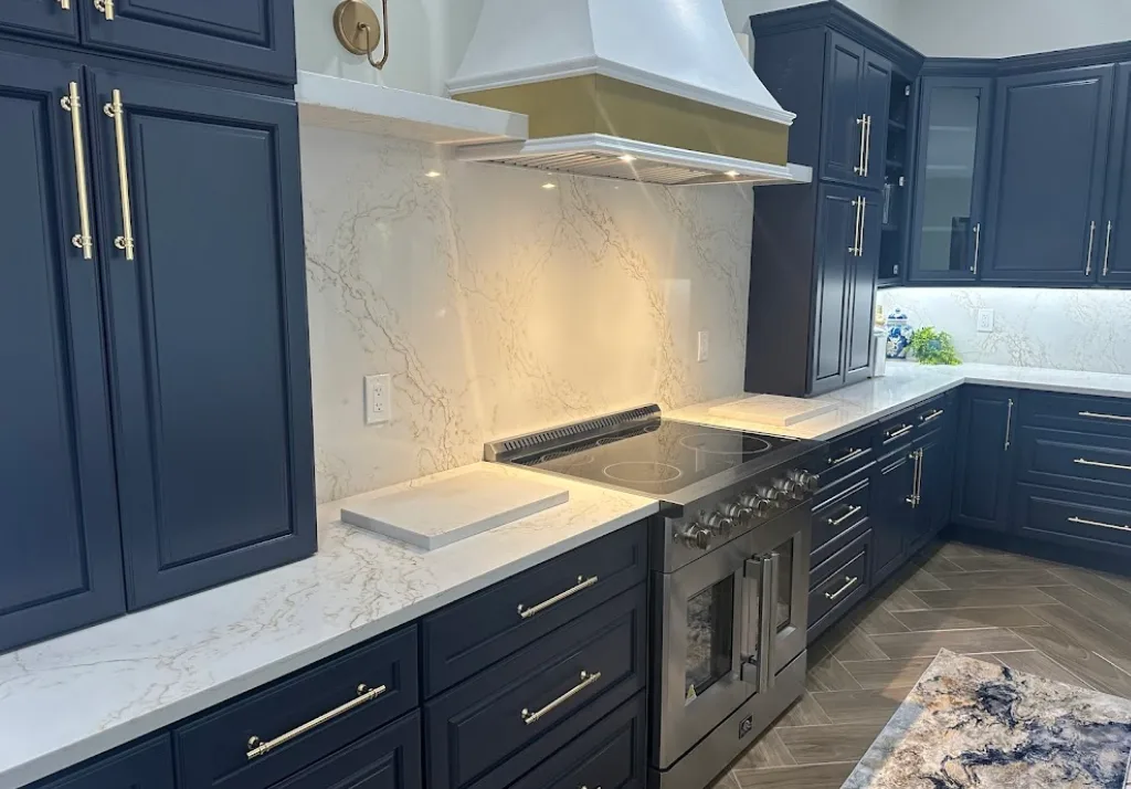 Sleek navy and brass kitchen with marble-like surfaces and modern appliances.