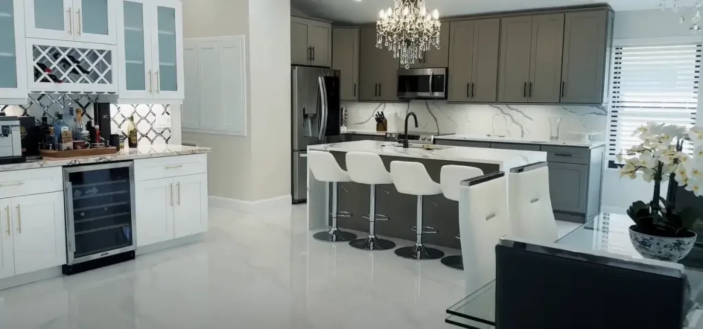 Modern kitchen showcasing a remodel checklist design with gray and white cabinets, marble countertops, a chandelier, and functional layout.