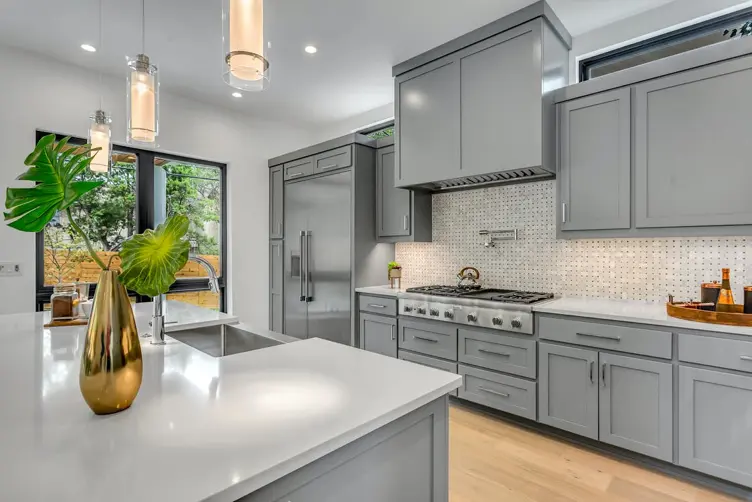 Modern kitchen with gray cabinets, wood flooring, and a marble island showcasing a well-planned kitchen remodel.